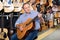 Adult guitarist is playing on acoustic guitar in music store.