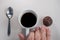 Adult hand picking up a cup of coffee between a metal spoon and a brigadier (traditional Brazilian children\\\'s party candy