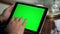 Adult hand swiping green tablet screen closeup. Man holding chroma key computer