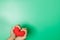 Adult hands holding red heart isolated on green background, health care, donate and family insurance concept