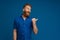 Adult handsome redhead bearded surprised man looking and pointing aside over isolated blue background