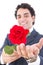 adult handsome smiling man in a suit holding a red rose and offers