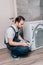 Adult handyman writing in clipboard and checking washing machine