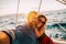 Adult happy caucasian couple take selfie picture yachting on a boat enjoying the sunset on the ocean - sun and sky in background