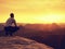 Adult hiker in black sit on mountain edge. Man enjoying evening