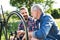 An adult hipster son and senior father repairing bicycle outside on a sunny day.