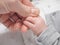 Adult holding infant's hand in closeup