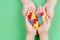 Adult and kid hands holding colorful heart on green background. World autism awareness day concept