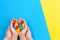 Adult and kid hands holding colorful heart on yellow and blue background. World autism awareness day concept