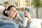 Adult lady with headphones listens music on phone at home