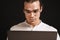 Adult long-haired man in glasses and shirt holding laptop