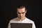 Adult long-haired man in glasses and shirt holding laptop