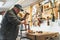 Adult male carpenter using brace - manual drill - to create holes in a piece of wood. Woodworking workshop interior.