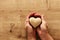 Adult male hands holding wooden shaped heart over table