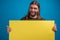 Adult male making funny faces to the camera while holding a yellow advertise banner