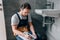 Adult male plumber with toolbelt writing in clipboard near broken sink