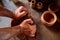 Adult male potter master modeling the clay plate on potter`s wheel. Top view, closeup, hands only.