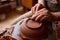 Adult male potter master modeling the clay plate on potter`s wheel. Top view, closeup, hands only.