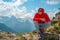 Adult male in red hoodie with hood enjoying beautiful view in mountainous area.