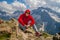 Adult male in red hoodie with hood enjoying beautiful view in mountainous area.