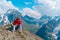 Adult male in red hoodie with hood enjoying beautiful view in mountainous area.