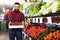 Adult male seller offering tomatoes in shop