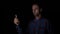 Adult male in shirt using facial recognition in a dark room to unlock his smartphone -