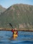 Adult male in sunglasses and baseball cap holding a paddle and rowing sitting in a kayak