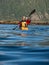 Adult male in sunglasses and baseball cap holding a paddle and rowing sitting in a kayak