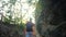 Adult male tourist walk on track in woods near rocks in rays of bright sun. Young man with backpack go hiking, trekking