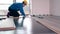 Adult male worker installing laminate floor, floating wood tile