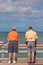 Adult males, fishing off a wood pier into tropical waters,