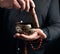 Adult man in a black shirt rotates a wooden stick around a copper Tibetan bowl of water. ritual of meditation