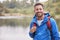 Adult man on a camping holiday standing by a lake smiling to camera, portrait, Lake District, UK