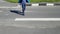 An adult man crossing a pedestrian crossing. He`s limping on one leg because he has cerebral palsy