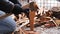 An adult man cuts tree stumps into small boards, preparing firewood for lighting a fire.