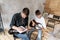 Adult man explains his son, who learn to play guitar, how to play melodies and songs using music sheet. Education with