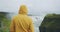 Adult man at Gullfoss Waterfall on Iceland in Icelandic nature. Tourist in yellow raincoat at famous tourist attraction