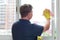 An adult man in rubber gloves washes windows