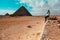 Adult man sitting on a rock with the great pyramids of giza in the background. Traveler traveling egypt in winter time, amazing