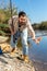 Adult man standing near river and pulling fish expressing emotions of dedication