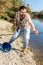 Adult man standing near river and pulling fish expressing emotions of dedication