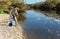 Adult man standing near river and pulling fish expressing emotions of dedication