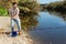 Adult man standing near river and pulling fish expressing emotions of dedication