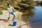 Adult man standing near river and pulling fish expressing emotions of dedication