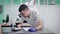 Adult man veterinarian is examining analysis under microscope in a vet clinic, making notes on a notebook