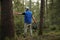 Adult man volunteer in red gloves removes plastic trash in forest, caring for environment