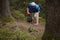 Adult man volunteer in red gloves removes plastic trash in forest, caring for environment