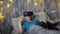 An adult man wearing virtual reality glasses plays with a cute pet, a black mongrel dog, while lying on a bed at home in