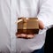 Adult man in a white shirt holds in his hand a square small box with a bow